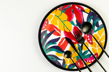 Top view of black tray, colorful plate, black cutlery on white background. Exotic plant plate, summer picnic. Flat lay, copy space.