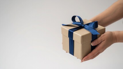Woman s hands holding a small brown gift box tied with a blue ribbon