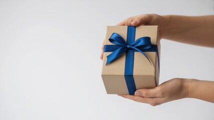 Woman s hands holding a small brown gift box tied with a blue ribbon