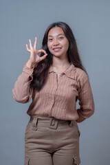 A confident Indonesian woman showing a positive gesture with her hand, forming an 