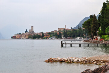 View of Lake Garda with Wooded Shore Old Jetties and Overcast Sky 