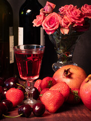 Still life with rose flowers, summer fruits, bottles of wine and a glass of wine. Pomegranate, cherry, sweet cherry, strawberry and watermelon. Alcohol. The still life is stylized as an old painting.