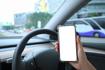 Hands using a mobile phone behind the wheel in a modern electric vehicle interior