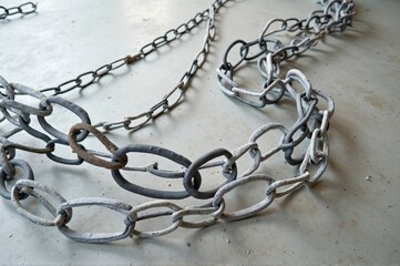 Obraz premium Rustic metal chains on concrete floor with shadows and texture details