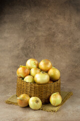 Lots of onions in a wicker basket. Vegetables in the form of onions on an abstract background. There is space for text.