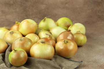 Lots of onions on a kitchen towel. There is space for text. Vegetables in the form of onions.