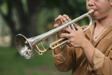 Male trumpet player performing solo in a peaceful green park
