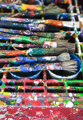 Konzept Kunst, Malen und Farbe: Authentisch mit Farbe bedeckte Pinsel auf einem farbverschmierten...