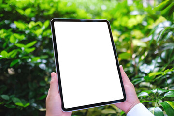 Mockup image of a woman holding digital tablet with blank white desktop screen in the nature...
