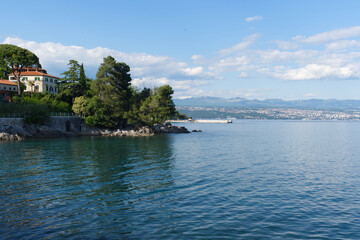 A picturesque view of the calm Adriatic Sea, featuring a lush green coastline with an elegant...