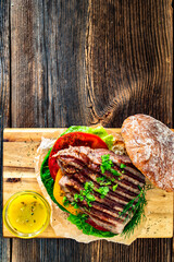 Takeaway sandwich with grilled beef steak and tomato served with vinaigrette sauce