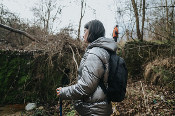 Hikers navigate through a serene winter woodland, wearing outdoor jackets and carrying backpacks....