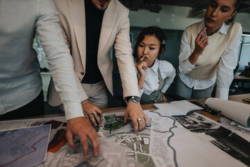 A diverse group of business coworkers intensely reviewing project plans at a busy office. The team...