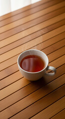 Photo of a steaming cup of hot tea rests on a warm wooden slatted table, inviting a moment of cozy refreshment