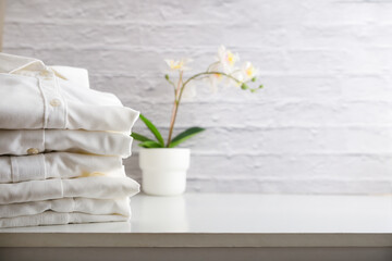 Stack of clean white shirts on a wooden cabinet