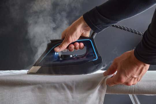 Detail of man ironing shirt with steam iron isolated background