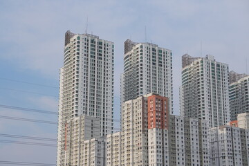 Fototapeta premium Modern residential skyscrapers stand closely together beneath cloudy sky in busy urban district during daytime.