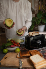 Morning routine in the kitchen woman uses toaster to quickly prepare a healthy toast with...