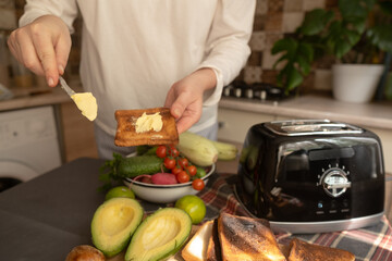 Modern morning routine woman places bread in toaster on a clean bright kitchen counter starting day with quick homemade breakfast.