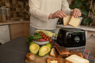 Electric appliances in action woman prepares toasts for breakfast using a convenient toaster easy...