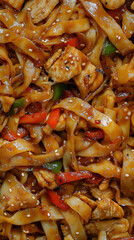 stir-fried flat rice noodles with chicken, vegetables, and sesame seeds, macro and full-frame texture shot, close-up texture, top view