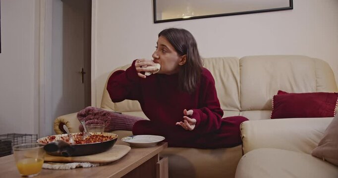 Young woman enjoying a delicious homemade wrap and orange juice in her cozy living room.