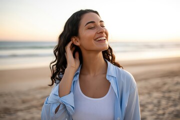 A happy young woman smiles on a beach at sunset