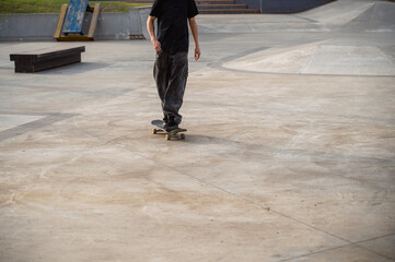 An unrecognizable skateboarder stands on a skateboard on a special skating area.