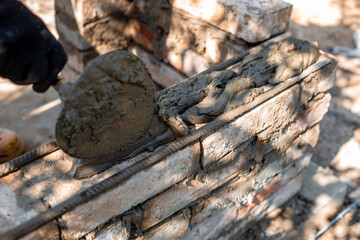 applying wet cement to brick structure showing texture and process of barbecue construction, close-up