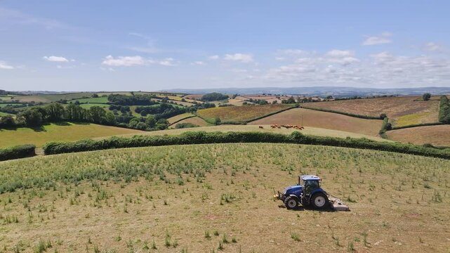 Farmer working with tractor in the fields of Devon from a drone, Torquay, England