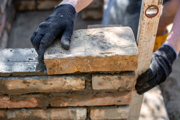 Close-up of leveling bricks during construction of brick structure using spirit level