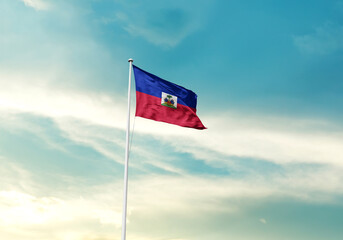 Haiti flag is waving on a tall flagpole among the clouds. Haitinational flag for independence day.
