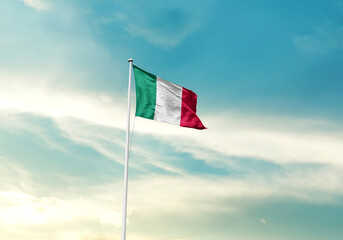 Italy flag is waving on a tall flagpole among the clouds. Italy national flag for independence day.