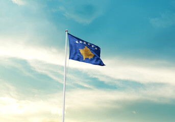 Kosovo flag is waving on a tall flagpole among the clouds. Kosovo national flag for independence day.