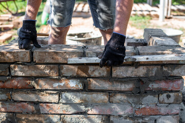 Close-up of leveling bricks during construction of brick structure using spirit level