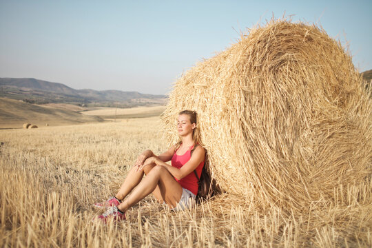 woman leaning on a bale of hay