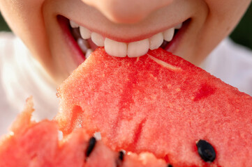 Close-up of teenager biting a juicy watermelon fruit.