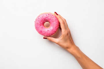 Female hand holding pink glazed donut with colorful sprinkles on white background. Ideal image for food design, advertising, bakery branding, menu visuals, or promotional dessert campaigns.