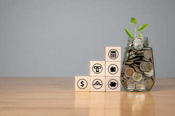 Coins in a glass jar and small house model on a table, symbolizing saving for home or property...