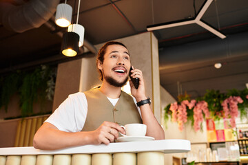 Young man enjoys remote work at a cozy cafe with a smile on his face