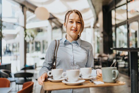 Waitress carrying coffee tray in a vibrant cafe environment during daytime