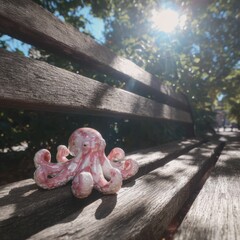 Decorative Ceramic Octopus Figure Displayed on a Wooden Park Bench Underneath the Sunlight with Natural Outdoor Scene