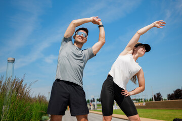 Stretching in the park on a sunny day with friends enjoying outdoor fitness