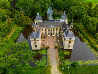 Aerial view of a historic castle surrounded by a forest, with vast green fields, winding waterways,...