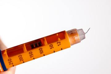 The needle on the tip of the orange insulin pen is bent on a white background