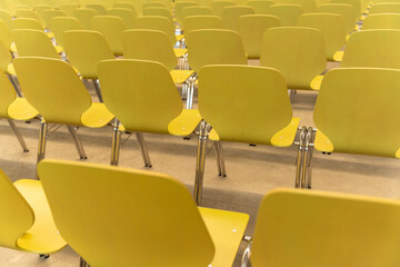 Empty rows of yellow chairs in a conference room. No people.
