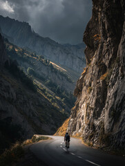 Cyclist climbing a steep alpine road at sunset, dramatic mountain scenery.