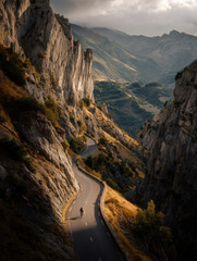 Cyclist climbing a steep alpine road at sunset, dramatic mountain scenery.