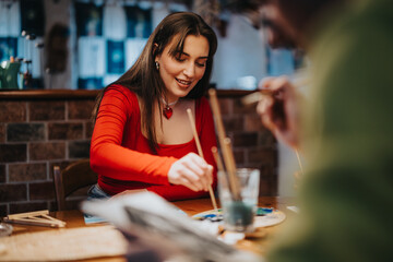 Group of friends creating art with brushes and paint in an inviting cozy atmosphere, enjoying their time together expressing creativity while bonding, surrounded by warm and friendly energy.
