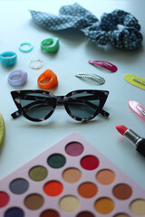 Green bag, various colorful jewelry, sunglasses, hair accessories and colorful make up on white background. Selective focus.